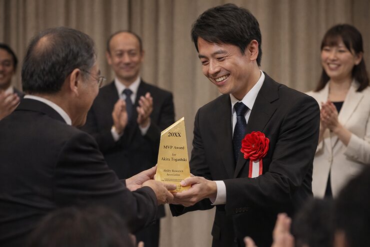 企業表彰で金色トロフィーを授与する社内表彰シーン